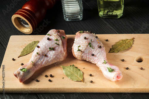 Сhicken legs on a cutting board with spices. The idea of cooking lunch or breakfast in a restaurant photo