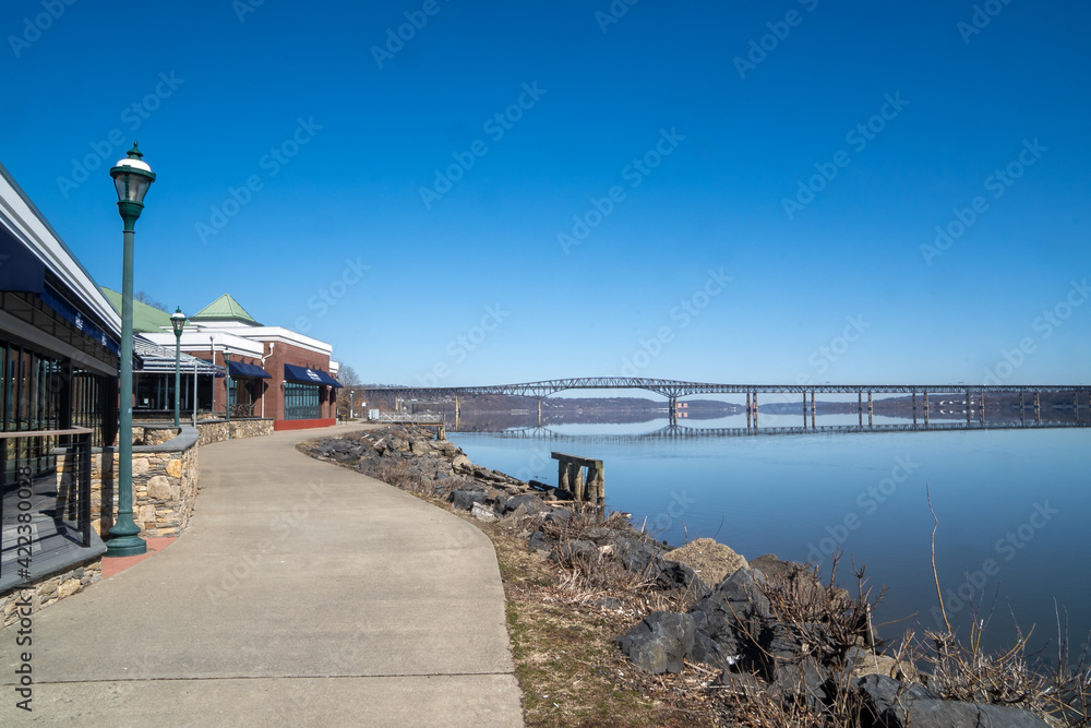 Newburgh, NY - USA - Mar. 21, 2021: View of Newburgh's trendy river front Blu Pointe restaurant, looking north up the Hudson River at the Hamilton Fish Newburgh Beacon Bridge.