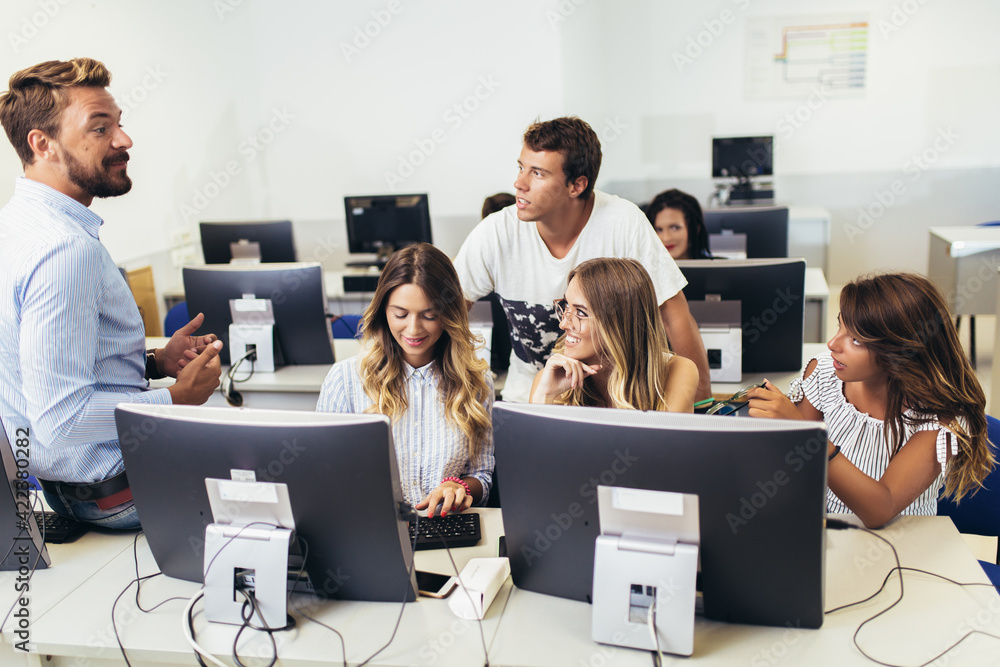 Fototapeta premium College students sitting in a classroom, using computers during class.