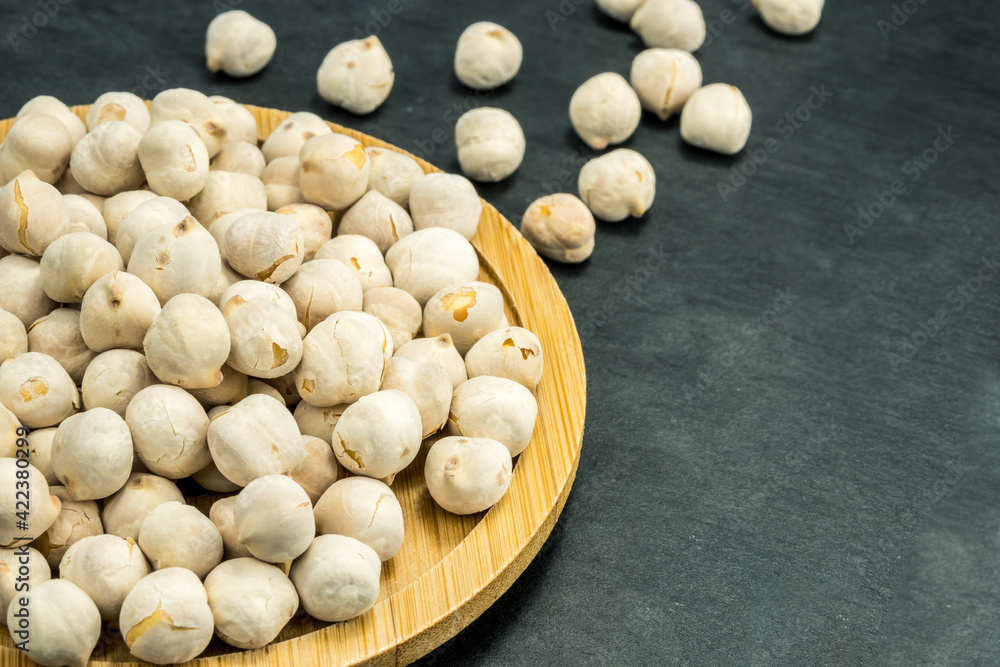 White chickpeas scattered on a black stone background.