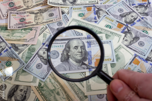 Φωτογραφία Magnifying glass on the background of bundle dollars - texture, background
