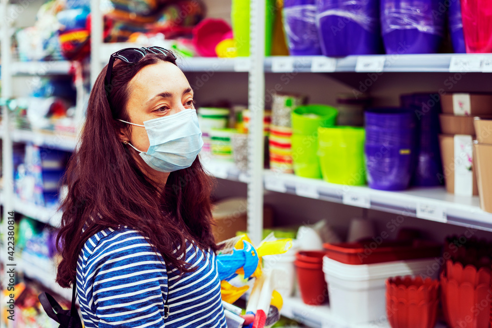 Woman in medical mask choosing goods in a store. Concept of shopping during quarantine at covid-19 pandemic. shopping at the time of the coronavirus. Beautiful young women in a flu mask. toned