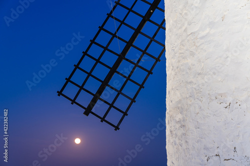 abstract detail view of a whitewashed windmill and wooden blade just after sunset with a full moon