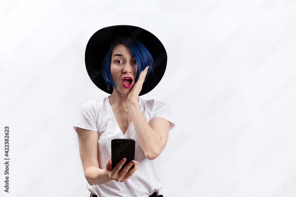 Fototapeta premium A woman in white tshirt surprisingly looking at a smartphone