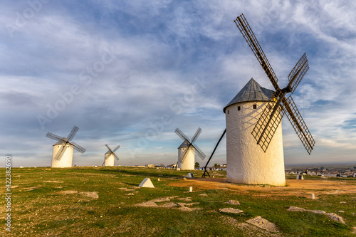 the historic white windmills of La Mancha above the town of Campo de Criptana in warm evening light