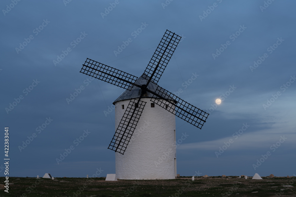 the historic white windmills of La Mancha above the town of Campo de Criptana at night under a full moon