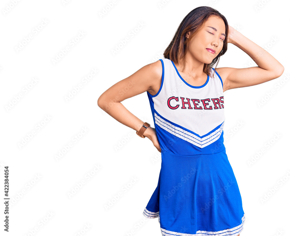 Young beautiful chinese girl wearing cheerleader uniform suffering of neck ache injury, touching neck with hand, muscular pain Young beautiful chinese girl wearing cheerleader uniform suffering of neck ache injury, touching neck with hand, muscular pain