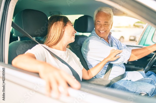 Middle age couple in love sitting inside the car going for a trip smiling happy and cheerful together © Krakenimages.com