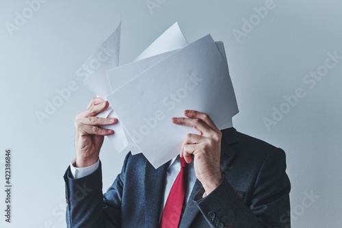 Businessman with too much paperwork, unrecognizable male businessperson behind papers photo