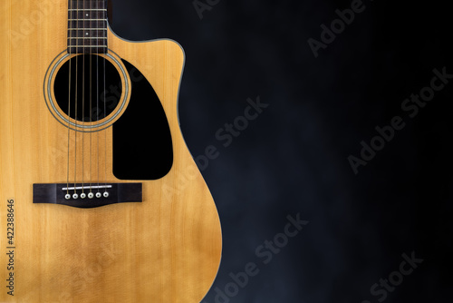 sound board of classic yellow acoustic guitar with black pickguard and strings near isolated black background