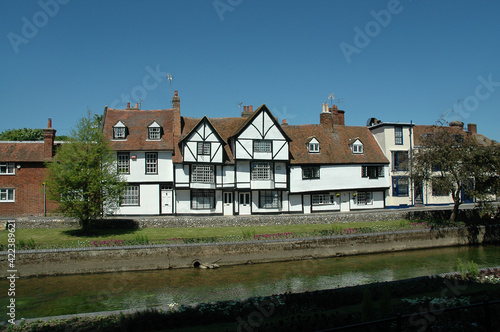 Row of half-timbered houses along the water with a blue sky
