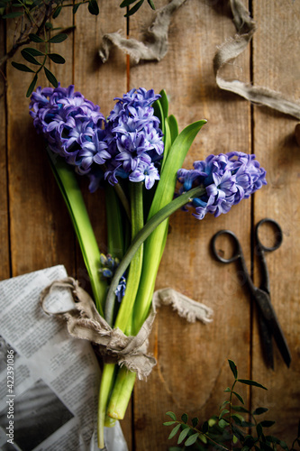 
bouquet of purple hyacinth flowers on a wooden background with old vintage scissors. abstract composition with purple flowers. flowers top view