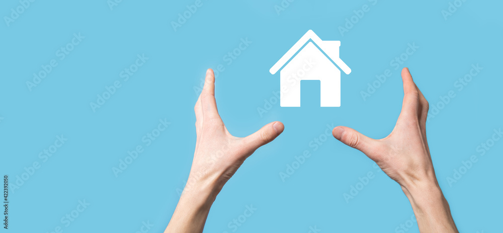 Male hand holding house icon on blue background. Property insurance and security concept.Real estate concept. Male hand holding house icon on blue background. Property insurance and security concept.Real estate concept.