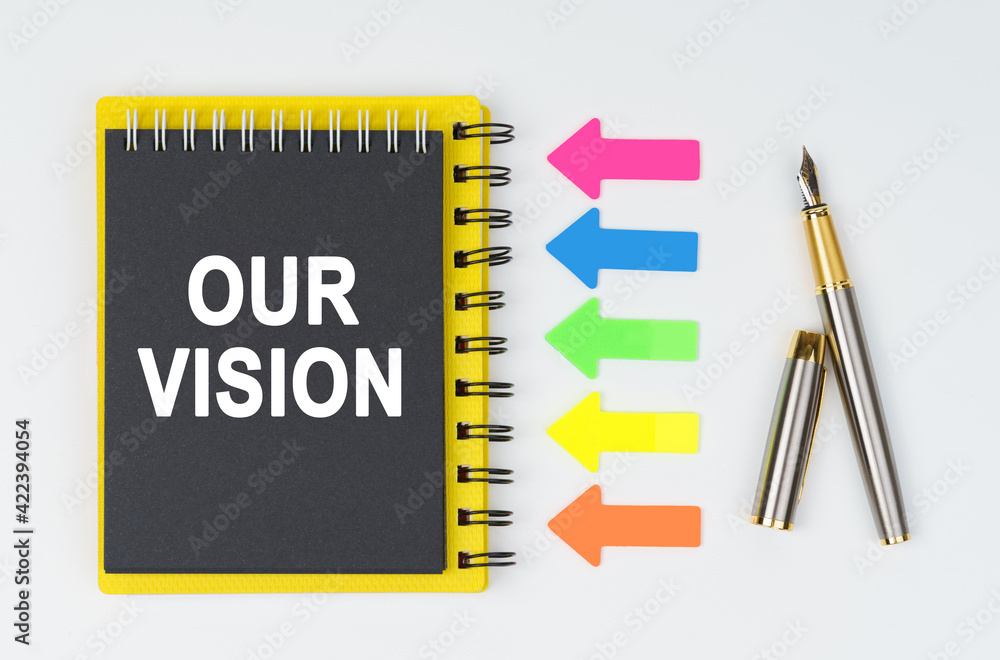 On a white background lies a pen, arrows and a notebook with the inscription - OUR VISION On a white background lies a pen, arrows and a notebook with the inscription - OUR VISION