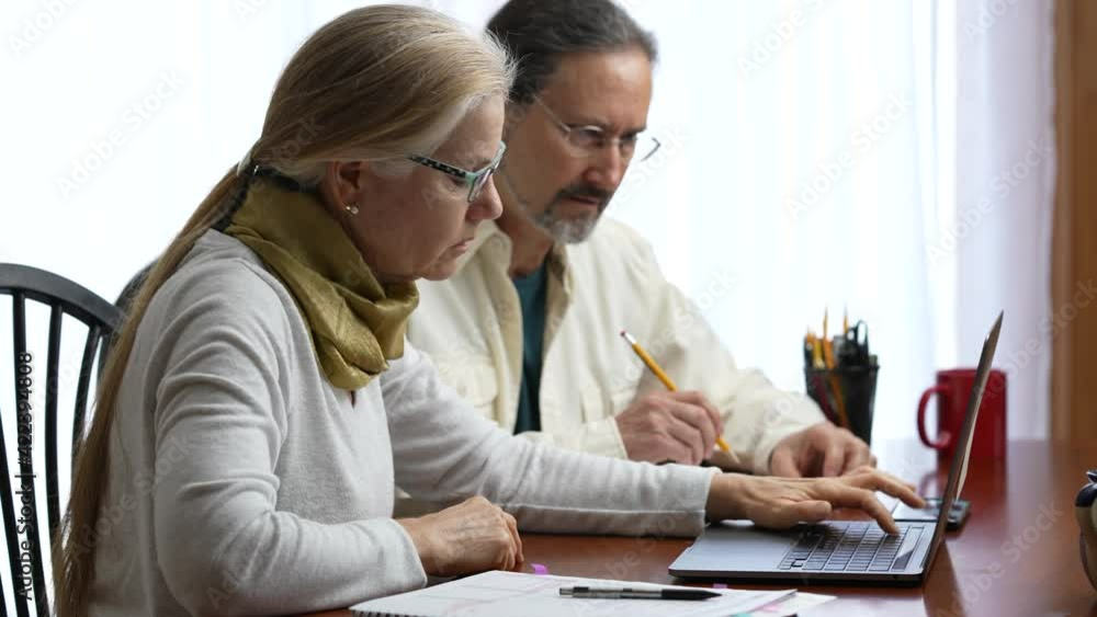 Mature couple at home working on laptop computer doing taxes and get great success. Concept of good news Mature couple at home working on laptop computer doing taxes and get great success. Concept of good news