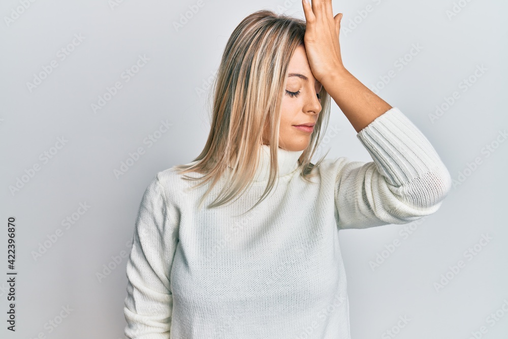 Beautiful blonde woman wearing casual turtleneck sweater surprised with hand on head for mistake, remember error. forgot, bad memory concept. Beautiful blonde woman wearing casual turtleneck sweater surprised with hand on head for mistake, remember error. forgot, bad memory concept.