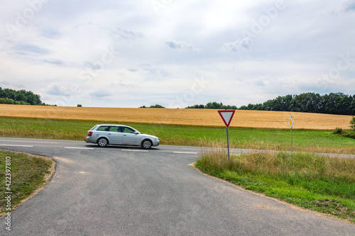 Auto auf Vorfahrtsstraße, Einmündung in Hauptstraße mit Verkehrszeichen "Vorfahrt gewähren" und "Vorfahrt"