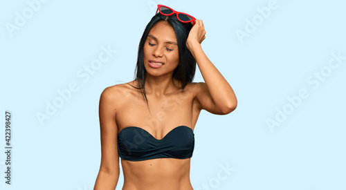 Young african american woman wearing bikini confuse and wonder about question. uncertain with doubt, thinking with hand on head. pensive concept. © Krakenimages.com