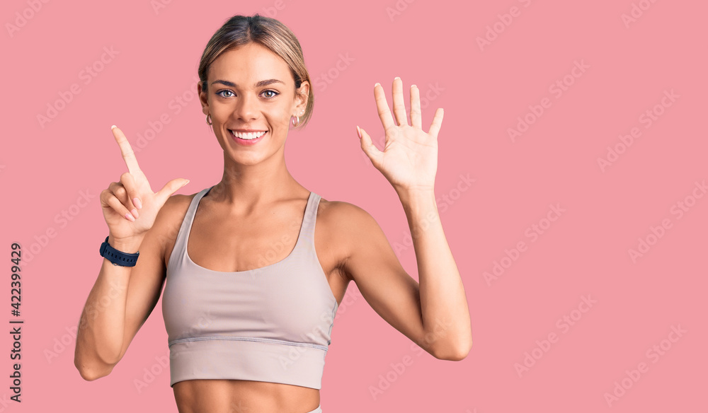 Beautiful caucasian woman wearing sportswear showing and pointing up with fingers number seven while smiling confident and happy. Beautiful caucasian woman wearing sportswear showing and pointing up with fingers number seven while smiling confident and happy.