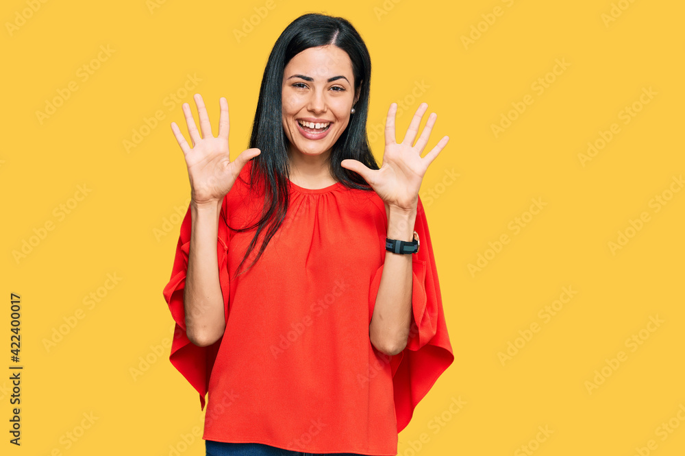 Beautiful young woman wearing casual clothes showing and pointing up with fingers number ten while smiling confident and happy. Beautiful young woman wearing casual clothes showing and pointing up with fingers number ten while smiling confident and happy.