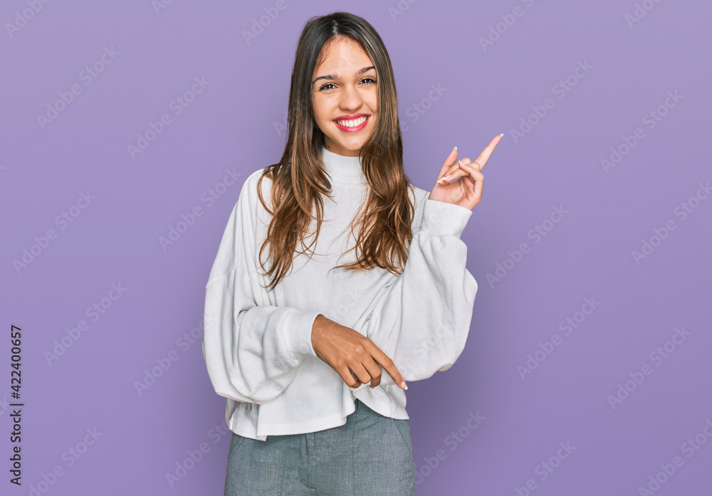 Young brunette woman wearing casual turtleneck sweater with a big smile on face, pointing with hand and finger to the side looking at the camera. Young brunette woman wearing casual turtleneck sweater with a big smile on face, pointing with hand and finger to the side looking at the camera.
