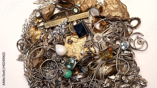 Pile of silver and gold jewelry with jewels rotating on a white background