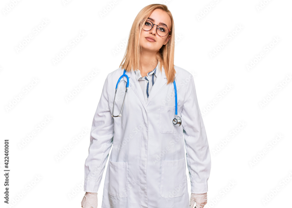 Beautiful caucasian woman wearing doctor uniform and stethoscope relaxed with serious expression on face. simple and natural looking at the camera. Beautiful caucasian woman wearing doctor uniform and stethoscope relaxed with serious expression on face. simple and natural looking at the camera.
