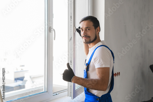 Male repairer installs a window and showing thumb