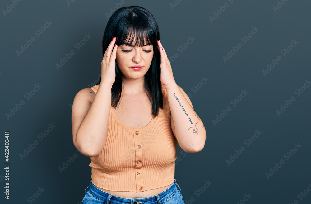 Young hispanic plus size woman wearing casual clothes with hand on head for pain in head because stress. suffering migraine. Young hispanic plus size woman wearing casual clothes with hand on head for pain in head because stress. suffering migraine.