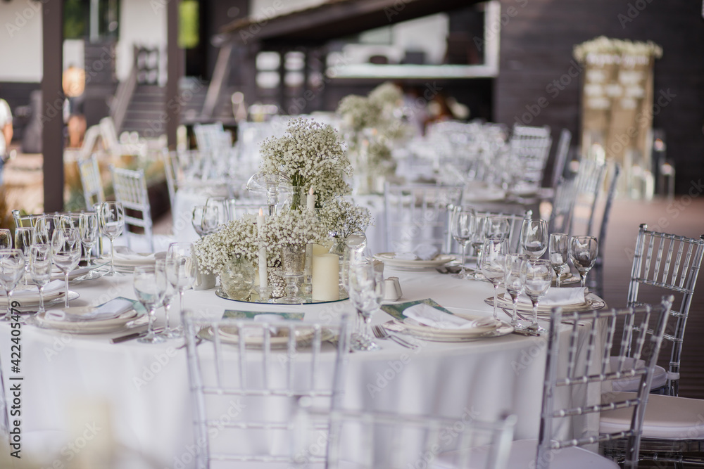 Close up of wedding table decoration with white wildflowers and candles. Tender decor. Celebrating concept.
