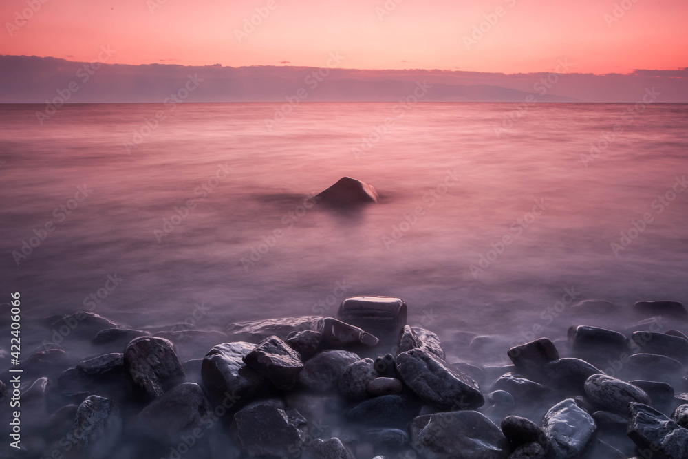 A pink sunset conveys a romantic feeling on a desert coastline with water A pink sunset conveys a romantic feeling on a desert coastline with water