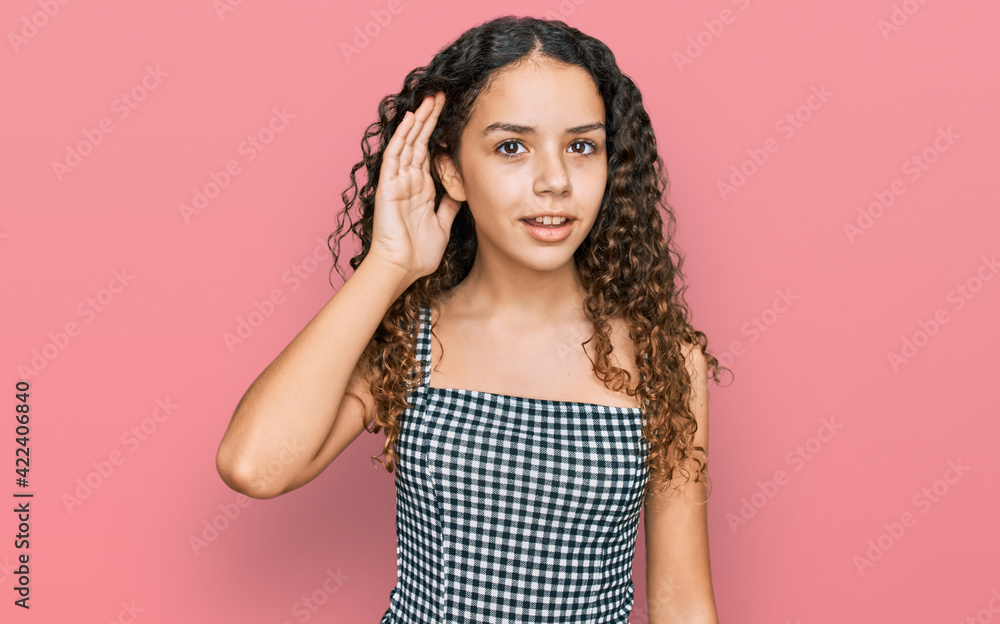 Teenager hispanic girl wearing casual clothes smiling with hand over ear listening an hearing to rumor or gossip. deafness concept. Teenager hispanic girl wearing casual clothes smiling with hand over ear listening an hearing to rumor or gossip. deafness concept.
