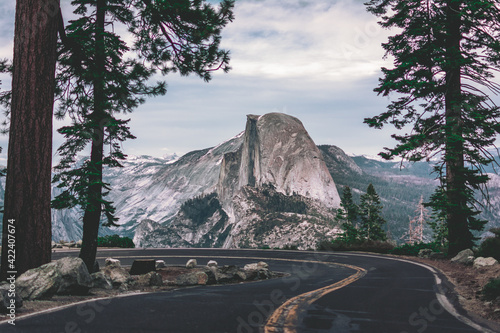 Beautiful view of winding Glacier Point Road with famous Half Dome summit in golden evening light at sunset in fall, Yosemite National Park, California, USA