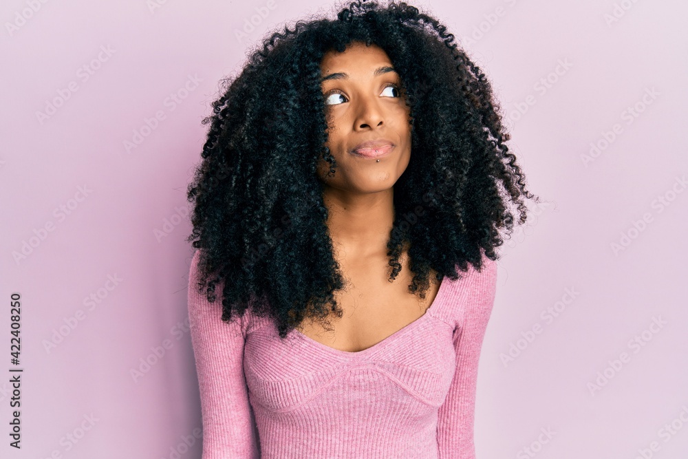 African american woman with afro hair wearing casual pink shirt smiling looking to the side and staring away thinking. African american woman with afro hair wearing casual pink shirt smiling looking to the side and staring away thinking.