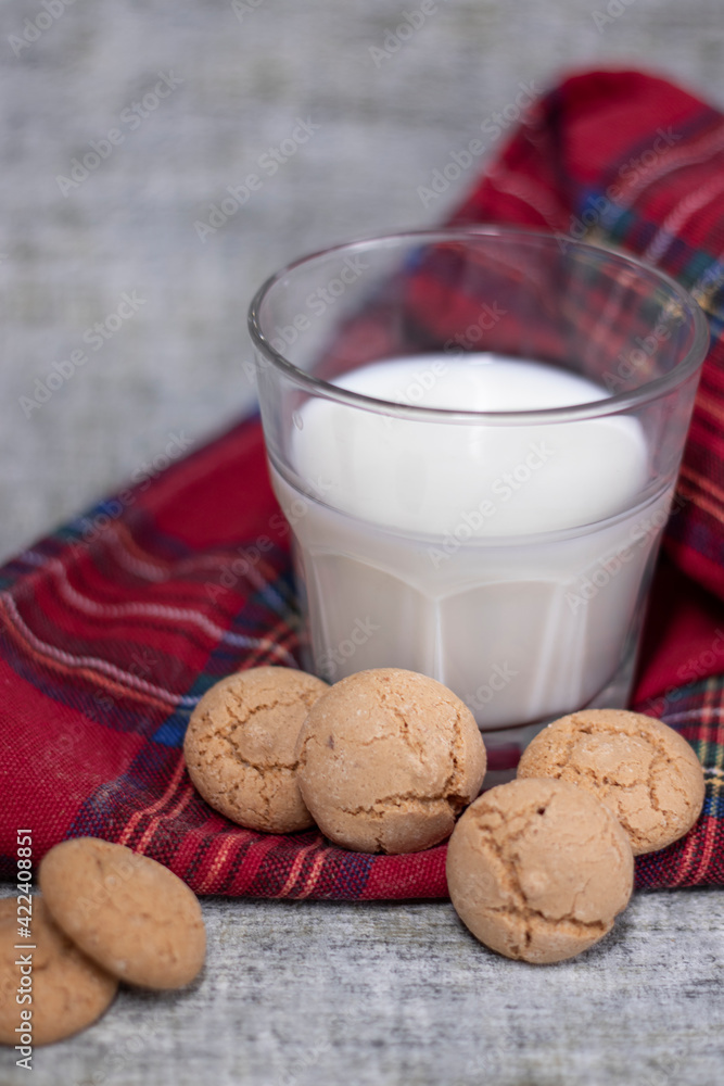 glass of milk near almond amaretti cookies on plaid red fabric tablecloth. healthy breakfast snack glass of milk near almond amaretti cookies on plaid red fabric tablecloth. healthy breakfast snack