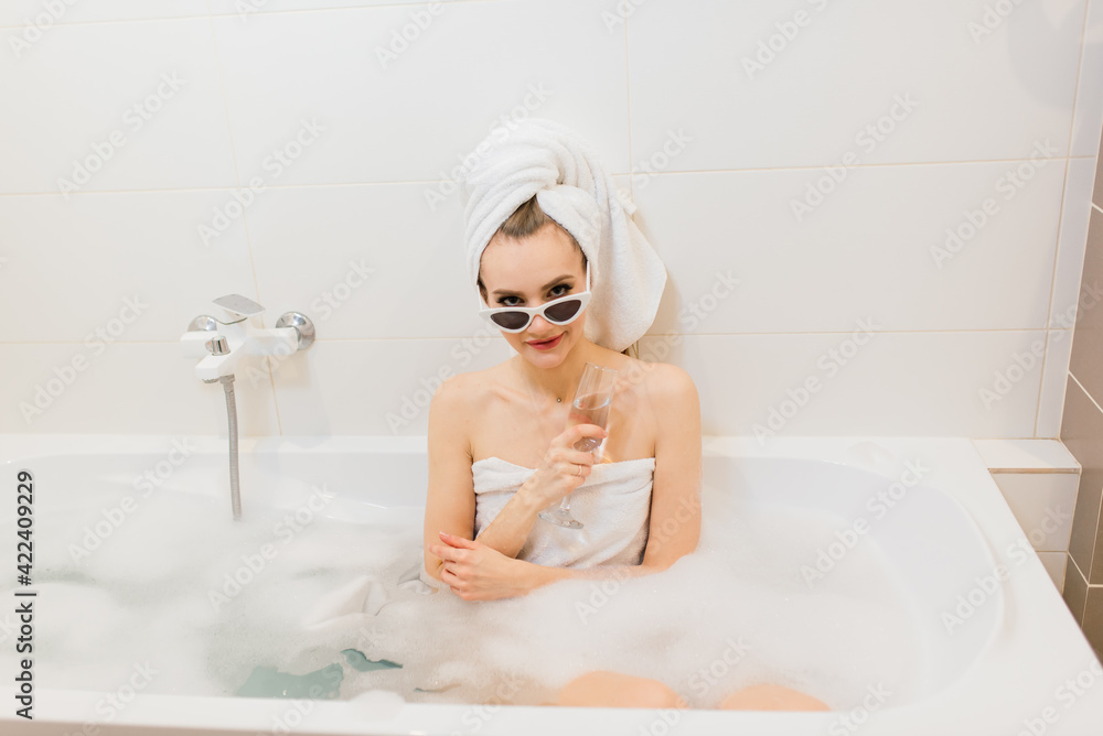 Lovely female with snow-white smile sits in the bathroom. Stylish woman in sunglasses at hotel Lovely female with snow-white smile sits in the bathroom. Stylish woman in sunglasses at hotel