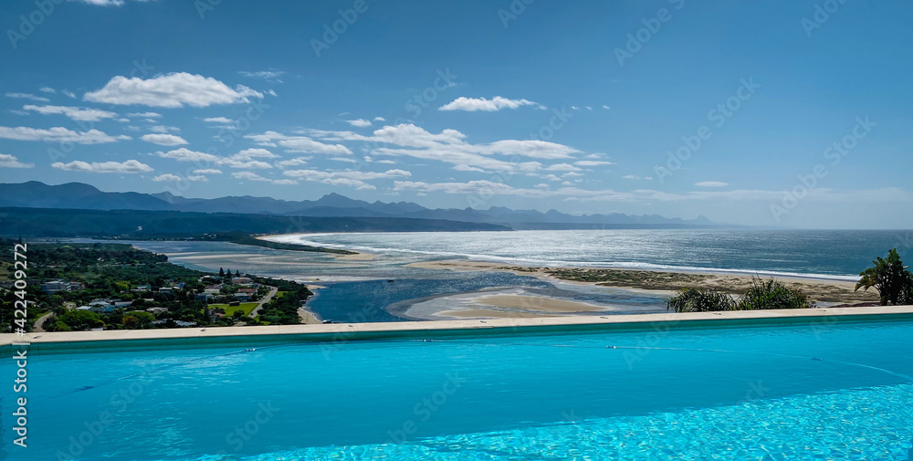 Panoramic view over Plettenberg Bay and Keurboomsrivier, South Africa with pool in foreground.