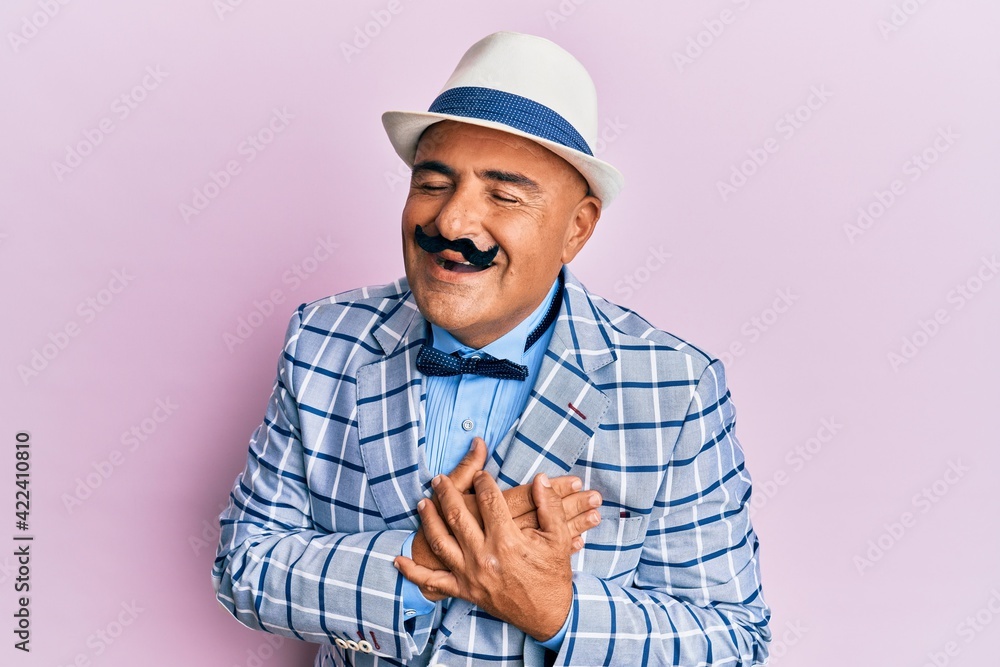 Mature middle east man with mustache wearing vintage and elegant fashion style smiling with hands on chest, eyes closed with grateful gesture on face. health concept.