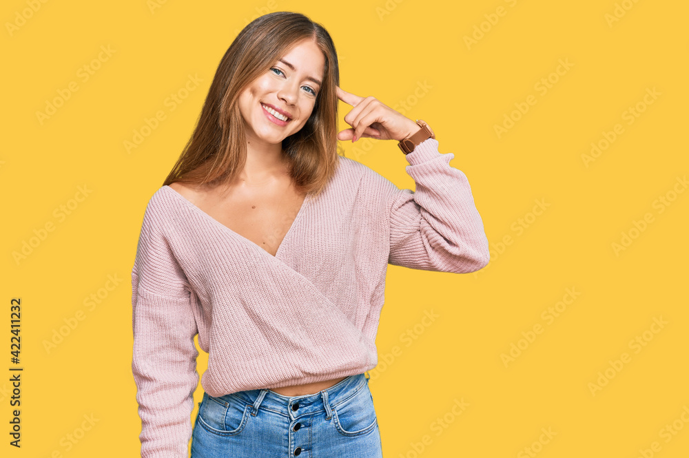 Beautiful blonde woman wearing casual winter pink sweater smiling pointing to head with one finger, great idea or thought, good memory Beautiful blonde woman wearing casual winter pink sweater smiling pointing to head with one finger, great idea or thought, good memory