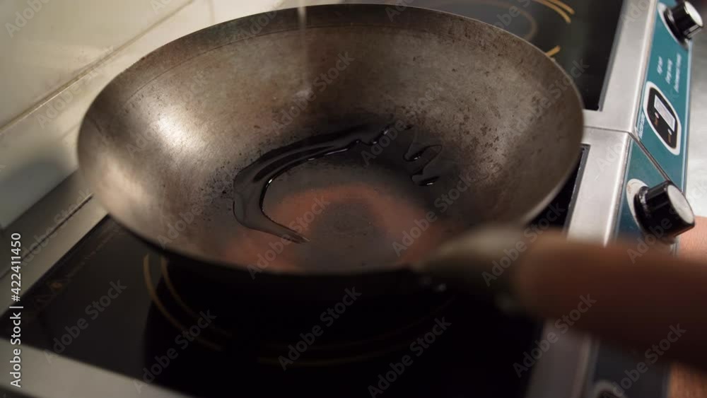 The cook pours sunflower oil into a frying pan, top view. The frying pan is on the stove, and oil for frying is poured into it. 4k