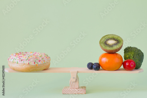 Fototapeta Naklejka Na Ścianę i Meble -  Donut vs. fruits and vegetables on wooden seesaw, diet and calories concept