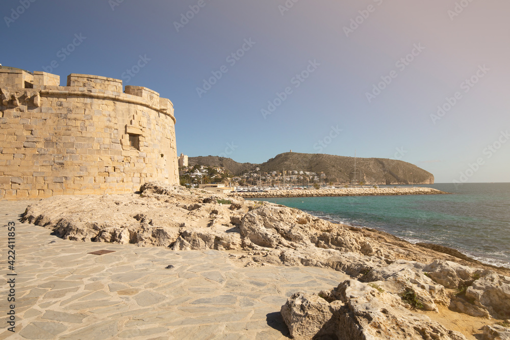 Mediterranean coast in the resort town of Moraira, overlooking a stone tower and a harbor with yachts, province of Alicante, Costa Blanca Spain