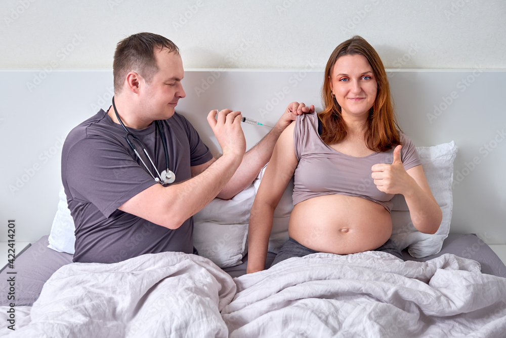 A husband gives an injection to a pregnant wife. A woman and a man with a syringe in bed, the concept of medical problems during pregnancy A husband gives an injection to a pregnant wife. A woman and a man with a syringe in bed, the concept of medical problems during pregnancy