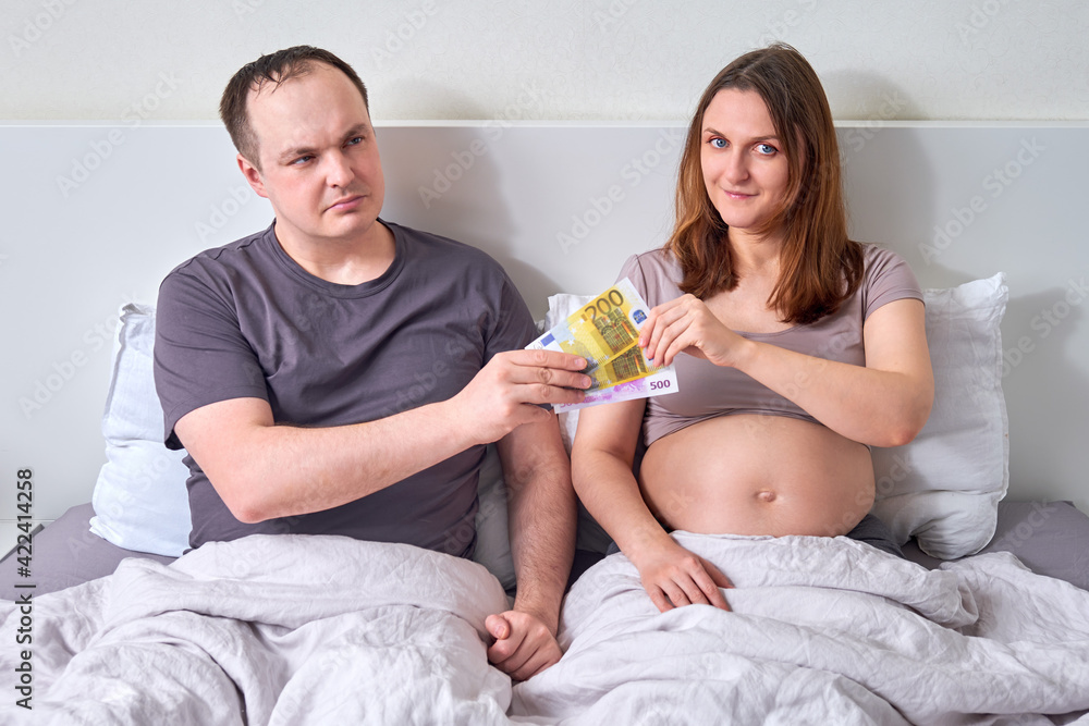 Man giving money in euros in bed to pregnant womanб concept Man giving money in euros in bed to pregnant womanб concept