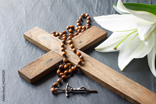Fotografia Cross, rosary and white lily on black marble background