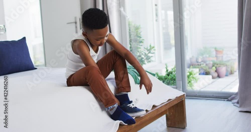 African american boy standing in bedroom getting dressed