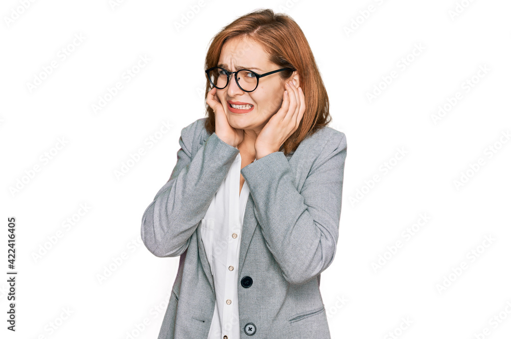 Young caucasian woman wearing business style and glasses covering ears with fingers with annoyed expression for the noise of loud music. deaf concept.