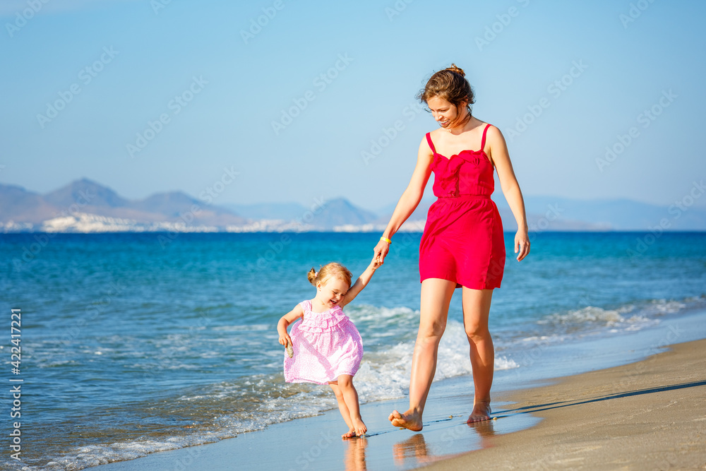 Naklejka premium Mother and little daughter walking on the sea beach in Greece