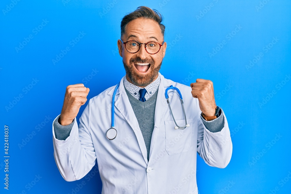 Handsome middle age man wearing doctor uniform and stethoscope celebrating surprised and amazed for success with arms raised and open eyes. winner concept. Handsome middle age man wearing doctor uniform and stethoscope celebrating surprised and amazed for success with arms raised and open eyes. winner concept.