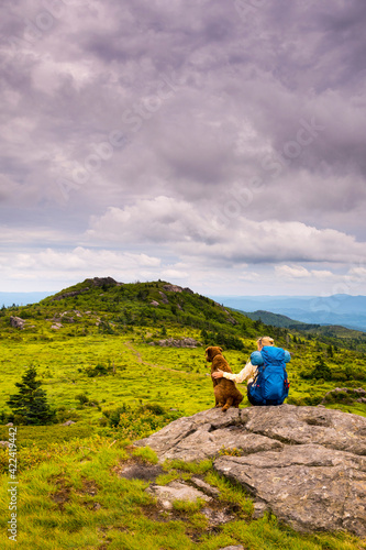 A woman and her dog hiking the Wilburn Ridge Tail section of the Appalachian Trail, Grayson Highlands, Mouth of Wilson, Virginia. photo